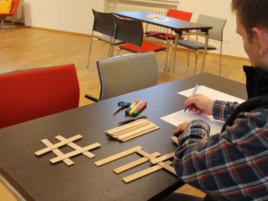 Ein Mann sitzt an einem Tisch mit Holzstäbchen