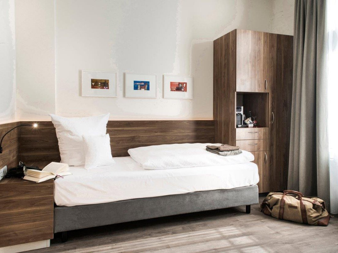 Einzelzimmer mit Boxspringbett und Kleiderschrank