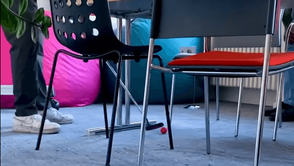 Ein Mann spielt zwischen einem Tagungstisch und Stühlen Minigolf