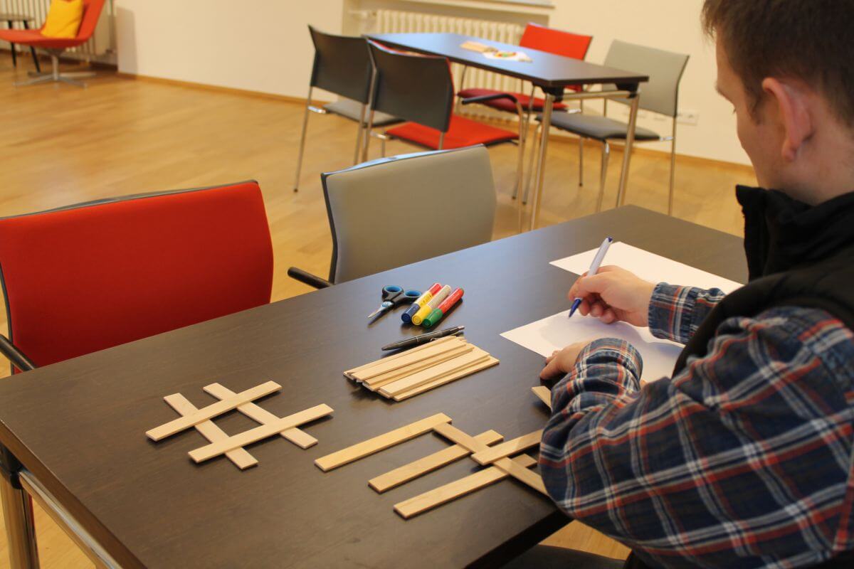 Ein Mann sitzt an einem Tisch mit Holzstäbchen